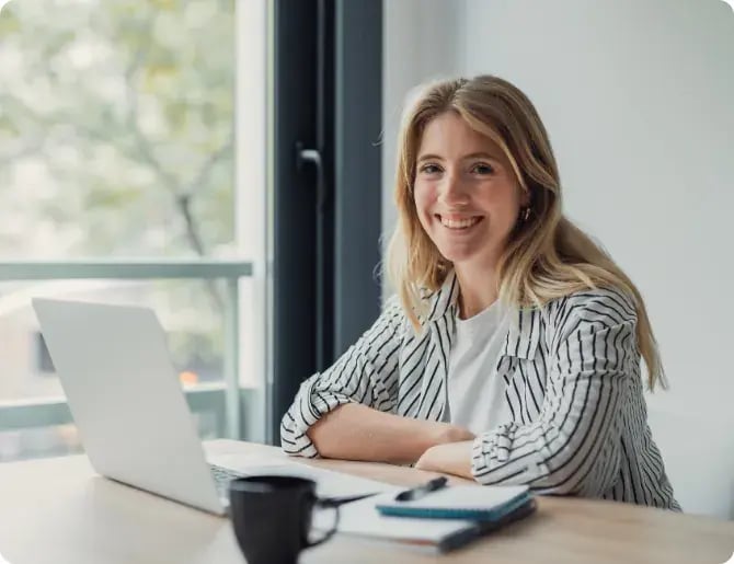 Smiling woman working on a laptop at her desk