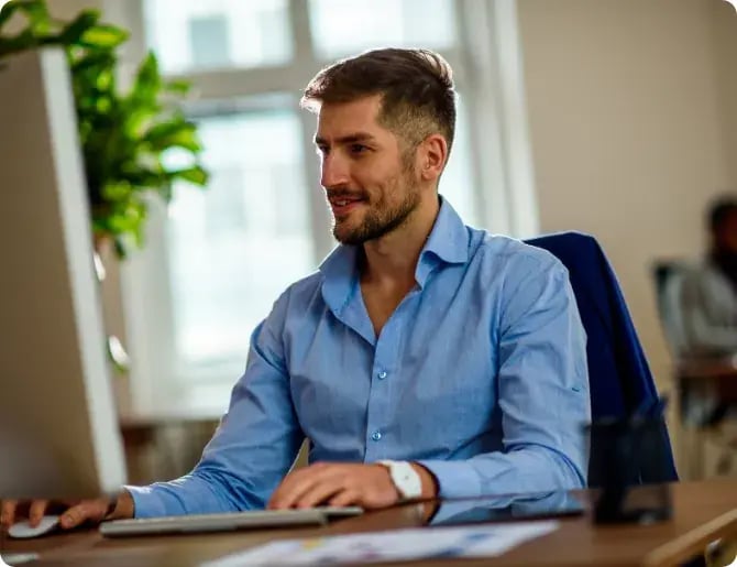 Man working at a desktop computer in a bright office